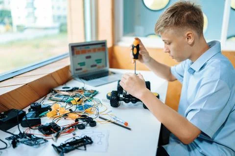 Student fixing robotics vehicle learn technology in STEM class. Edification. 库存照片