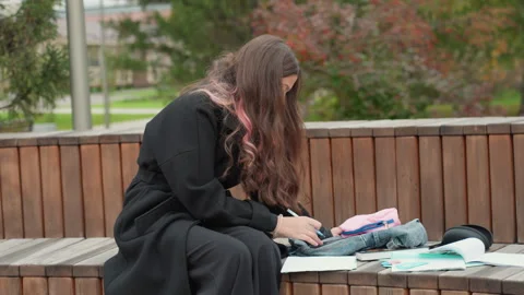 Student focused on exam preparation outdoors. Female student diligently Stock Footage 334068561