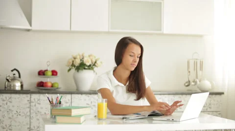 Student girl sitting at table using laptop drinking juice and smiling Stock Footage 34196242