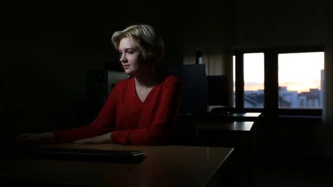 Student girl working on the computer, window sunset until late at night in the Stock Footage 82352292