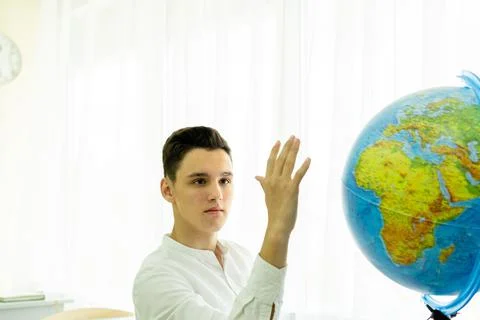 A student giving an answer in class with his hand raised is sitting at a table Stock Photos