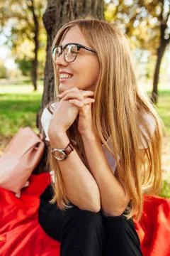 Student with glasses, resting after class in the Park sitting on a red blanke Stock Photos