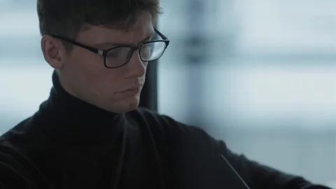 Student with glasses writes in a notebook, sitting in a bright room Stock-Footage 125011481