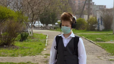 Student guy in face mask walk on the street with headphones listens to music  Stock Footage 127834739