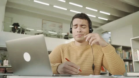 The student guy is tired of studying remotely at the laptop, disappointed from Stock Footage 154377221
