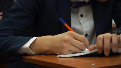 The student guy writes in a notebook. He is nervous and doubt the correct answer Stock Footage 100033721