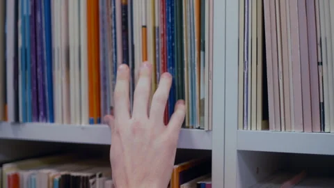 Student hand searching for a book on a library bookshelf Stockbeeldmateriaal 335123991