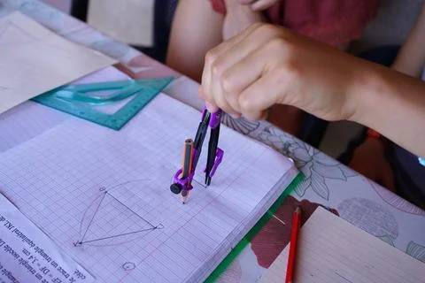 Student hand using a drawing compass to construct geometric shapes during a.. Stock Photos