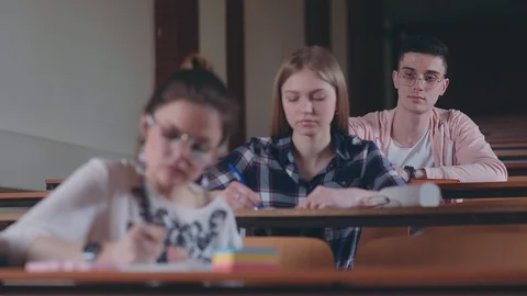 Student handed a note to classmate, sitting on top row of the audience Stock Footage 88807196