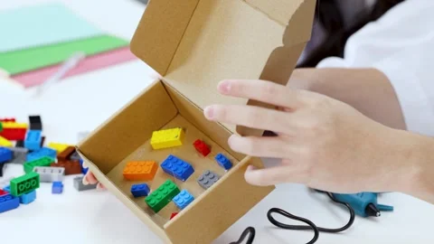 Student Hands Building Science Project with Toy Bricks and Cardboard Box Stock Footage 341642982