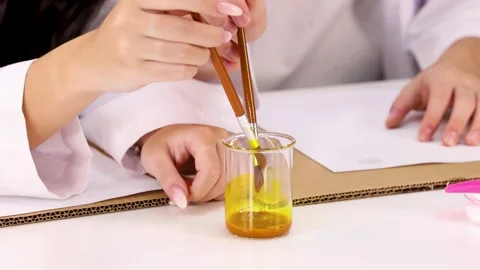 Student Hands Mixing Yellow Liquid in Beaker During Science Experiment Stock Footage 346195259