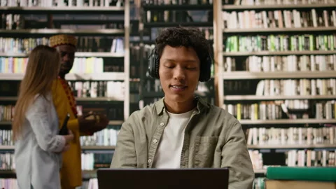 Student with headphones reading open book and studying with focus music Stock Footage 337229557