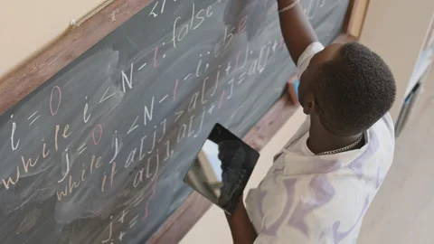 Student Holding Digital Tablet and Writing Script on Chalkboard Stock Footage 257064088