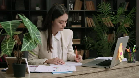 Student intern in classic suit sitting at an office table. Woman analyzing Stock Footage 305384110