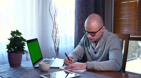 Student learnig in home. He is using laptop, making some notes Stock Footage 61281435