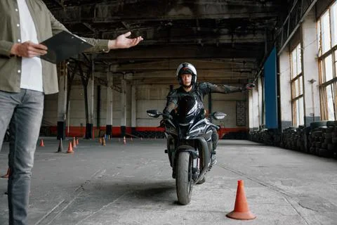 Student learning how to drive motorcycle with one hand 库存照片