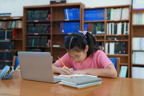 Student learning online class by using laptop computer and writing notebook a Fotos de archivo
