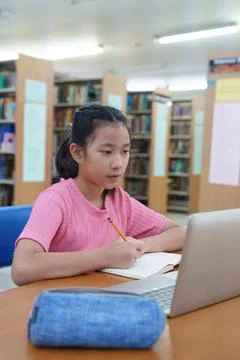 Student learning online class by using laptop computer and writing notebook a Stock Photos