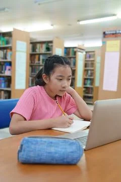 Student learning online class by using laptop computer and writing notebook a Fotos de archivo