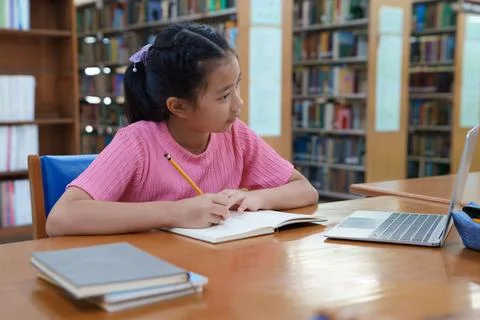 Student learning online class by using laptop computer and writing notebook a Stock Photos