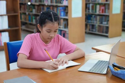 Student learning online class by using laptop computer and writing notebook a Fotos de archivo