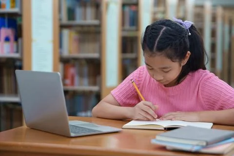 Student learning online class by using laptop computer and writing notebook a Stock Photos