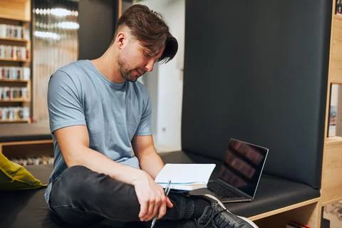 Student learning in university library. Young man reading his notes. Man us.. Stock Photos