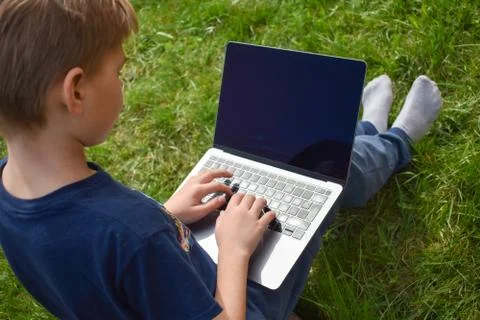 The student learns in the garden on the computer. The online schooling Stock Photos