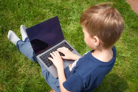 The student learns in the garden on the computer. The online schooling Stock Photos