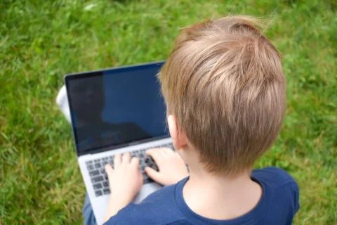 The student learns in the garden on the computer. The online schooling Stock Photos