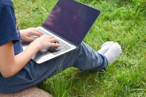 The student learns in the garden on the computer. The online schooling Stock Photos