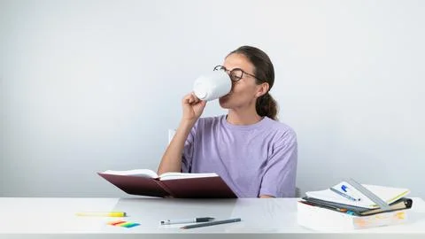 A student learns lessons and drinks tea while reading a textbook - a break for 스톡 사진