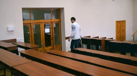 The student leaves the lecture hall. He turns off the light when leaving. Stock Footage 63104047