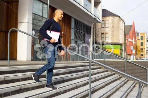 Student leaving college holding his textbooks and rucksack Stock Photos