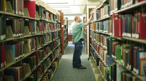 Student in library, pulling book off shelf Vídeos de archivo 8838348