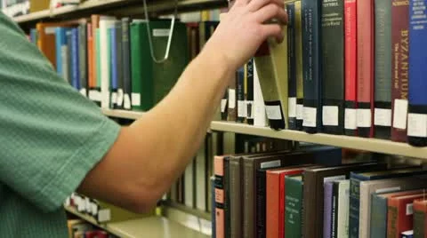 Student in library, pulling book off shelf Vídeos de archivo 8851077