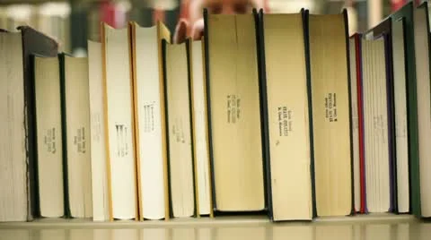 Student in library, pulling book off shelf Video stock 8853535