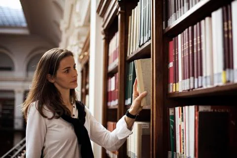 Student looking for a book in library. Stock Photos