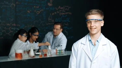 Student looking at camera while diverse group doing experiment. Edification. 스톡 사진