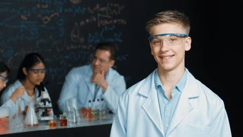 Student looking at camera while diverse group doing experiment. Edification. 스톡 사진