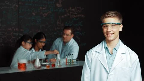 Student looking at camera while diverse group doing experiment. Edification. 스톡 사진