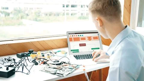 Student looking at laptop screen while coding engineering prompt. Edification. Stock Photos