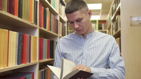 A student looking for a suitable book to prepare for an exam. University Library Stock Footage 219676028