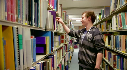 Student Looking Through Books in a Library Stock Footage 61638599