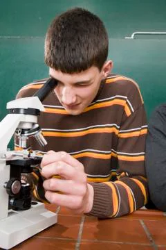 A student looking through a microscope in biology class 스톡 사진