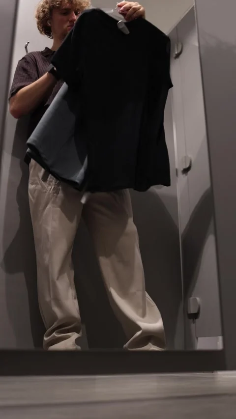Student looks at different clothes and compares items before choosing what to bu Video stock 344855892