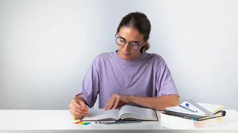 The student makes notes and bookmarks in the textbook Stock Photos