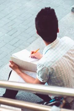 Student making a notes sitting on stairs outside of university Stock Photos