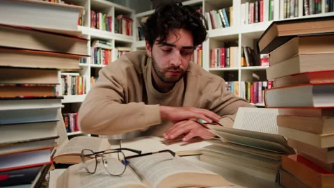Student Man Sleeping at the Library. Tired overworked young man sleeping near Stock Footage 229891132