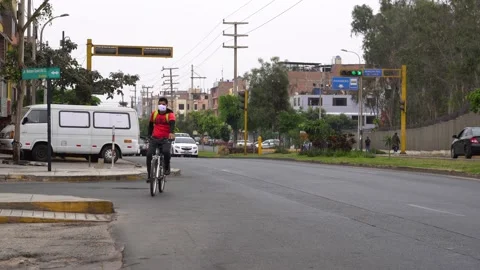 Student with mask and backpack riding a bicycle around the city Video stock 148337620